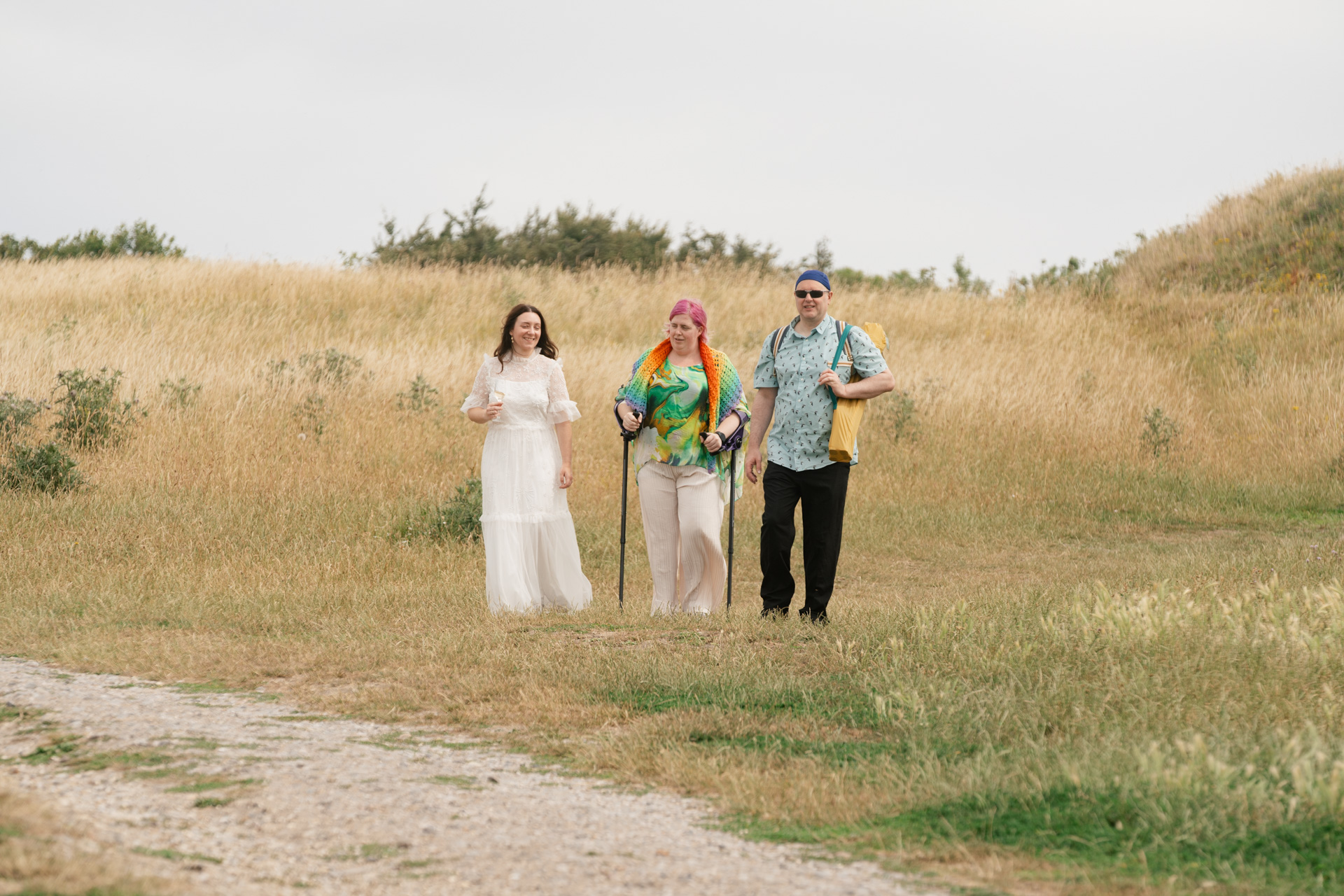 Couple walking off with a guest in colourful dress